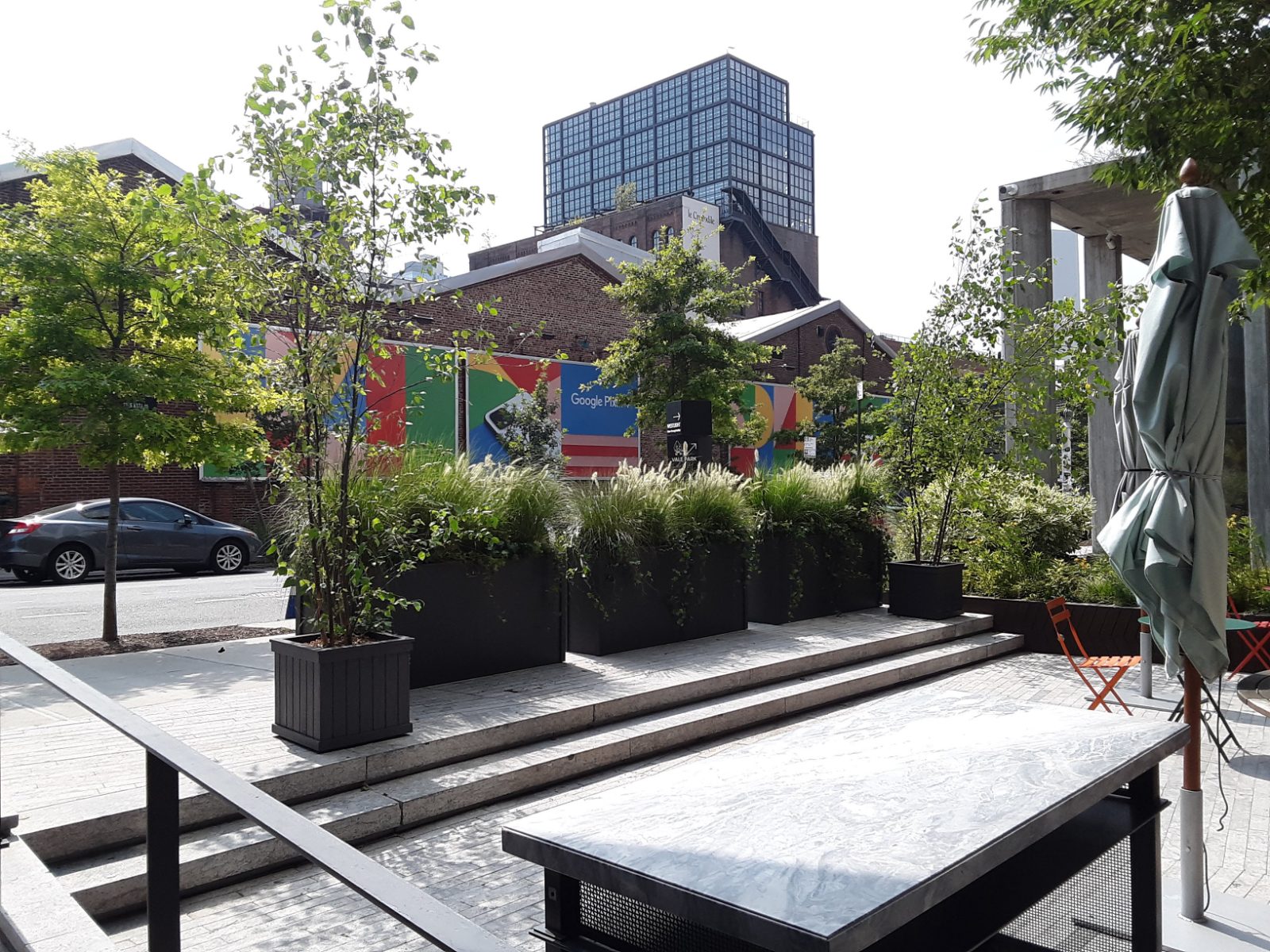 Streetside planters of ornamental grasses and young birch beside a café terrace